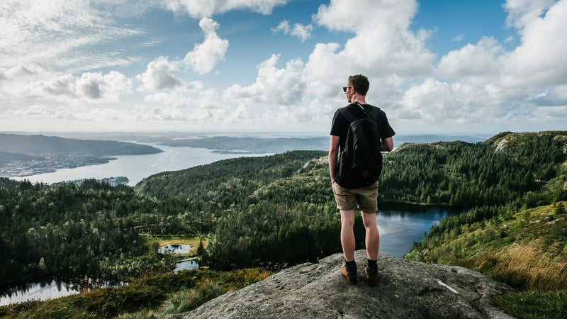 Hombre con polera mirando un lago desde la cumbre