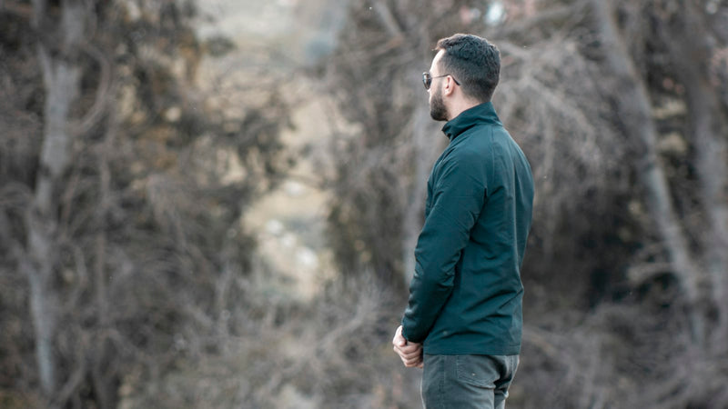 Hombre con polar verde en un bosque de otoño