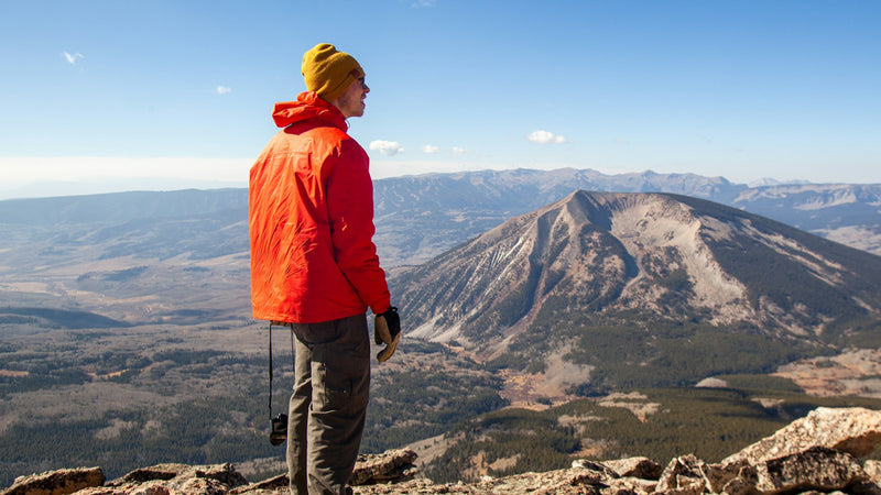 Hombre con chaqueta naranja frente a la cordillera