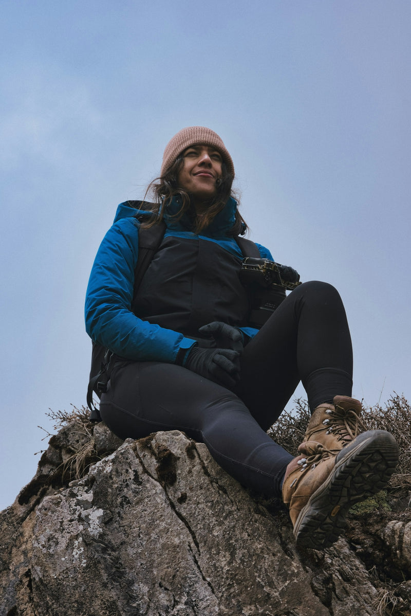 Mujer con gorro y guantes descansando en la montaña